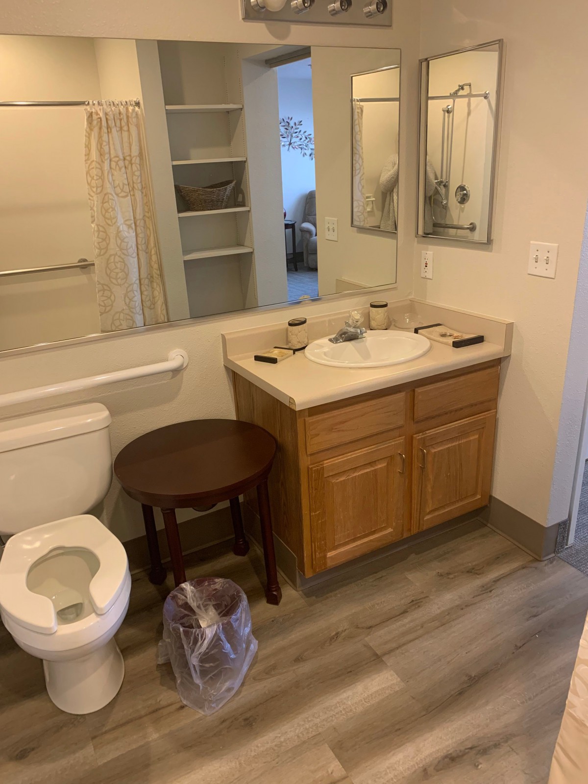 A clean bathroom interior with a sink, toilet, and wooden cabinet.