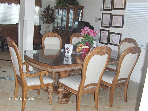 A classic dining room setup with a wooden table and chairs, adorned with flowers.