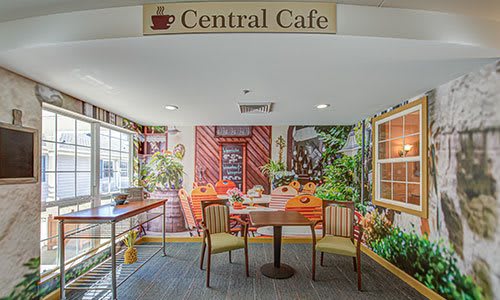 A cozy cafe interior with colorful wall art and seating arrangement.