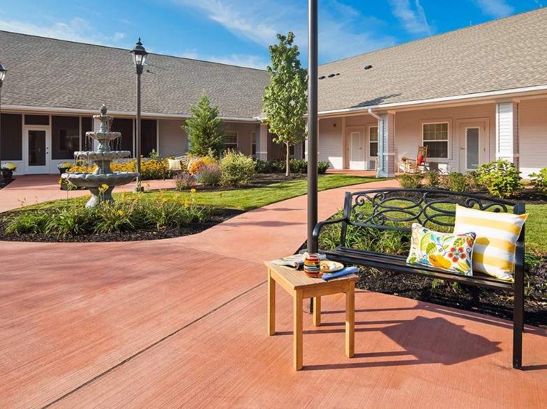 A serene courtyard with a fountain, surrounded by well-maintained landscaping and benches for relaxation.