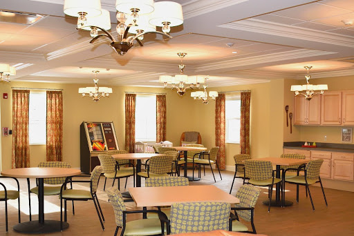 A cozy dining area with tables and chairs, illuminated by chandeliers, perfect for community gatherings.