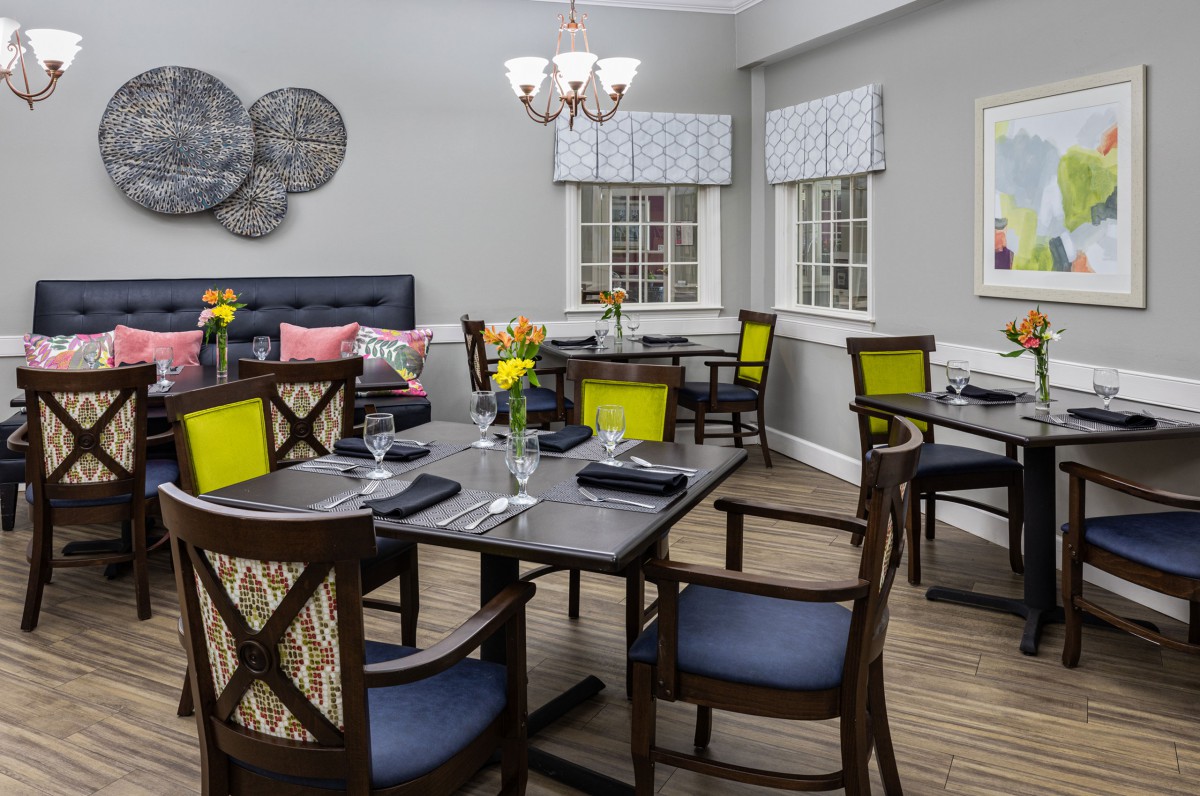 A modern dining room featuring neatly arranged tables and chairs with bright decor accents.
