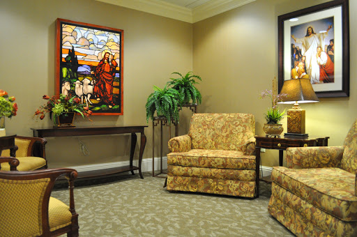 A cozy lounge area featuring patterned chairs, a table, and decorative stained glass artwork.