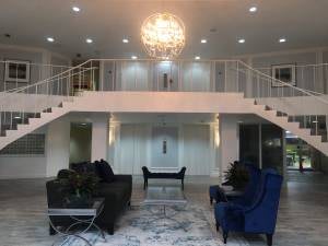 A luxurious modern living room with a grand chandelier and elegant furniture.