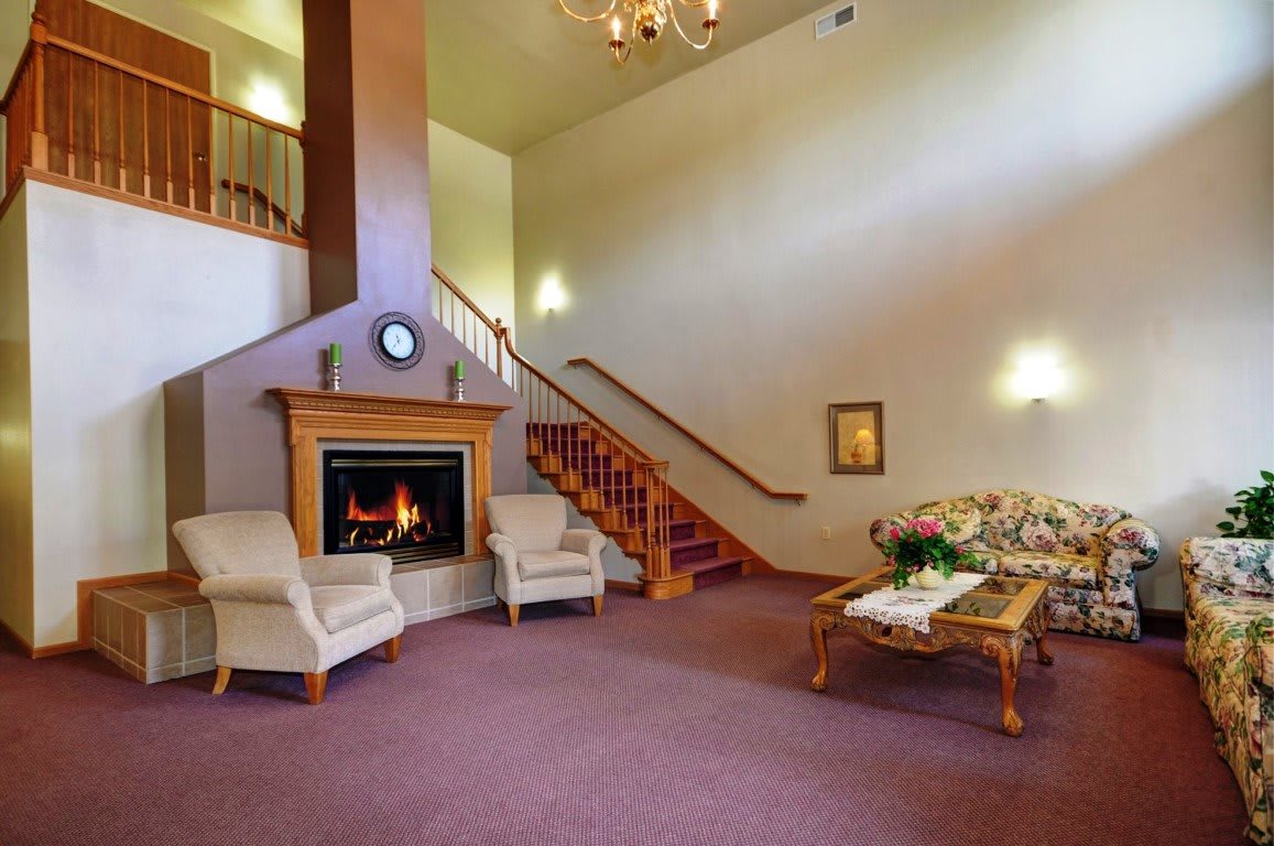 A cozy living room with a fireplace, elegant furniture, and a staircase leading to an upper level.