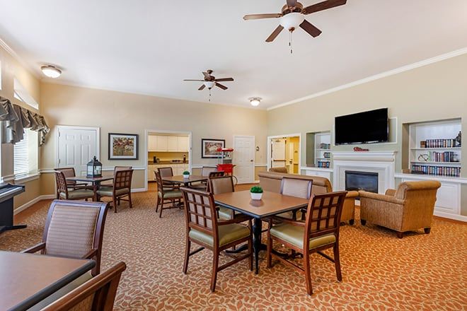 A cozy living room with dining tables, chairs, a fireplace, and a television.