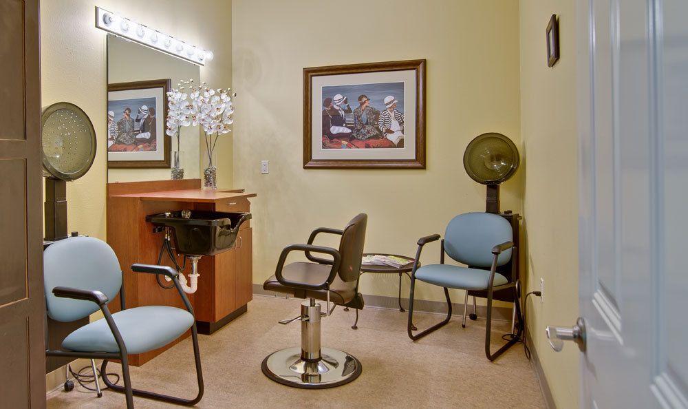 A cozy hair salon interior with chairs, a mirror, and a vintage hair dryer.