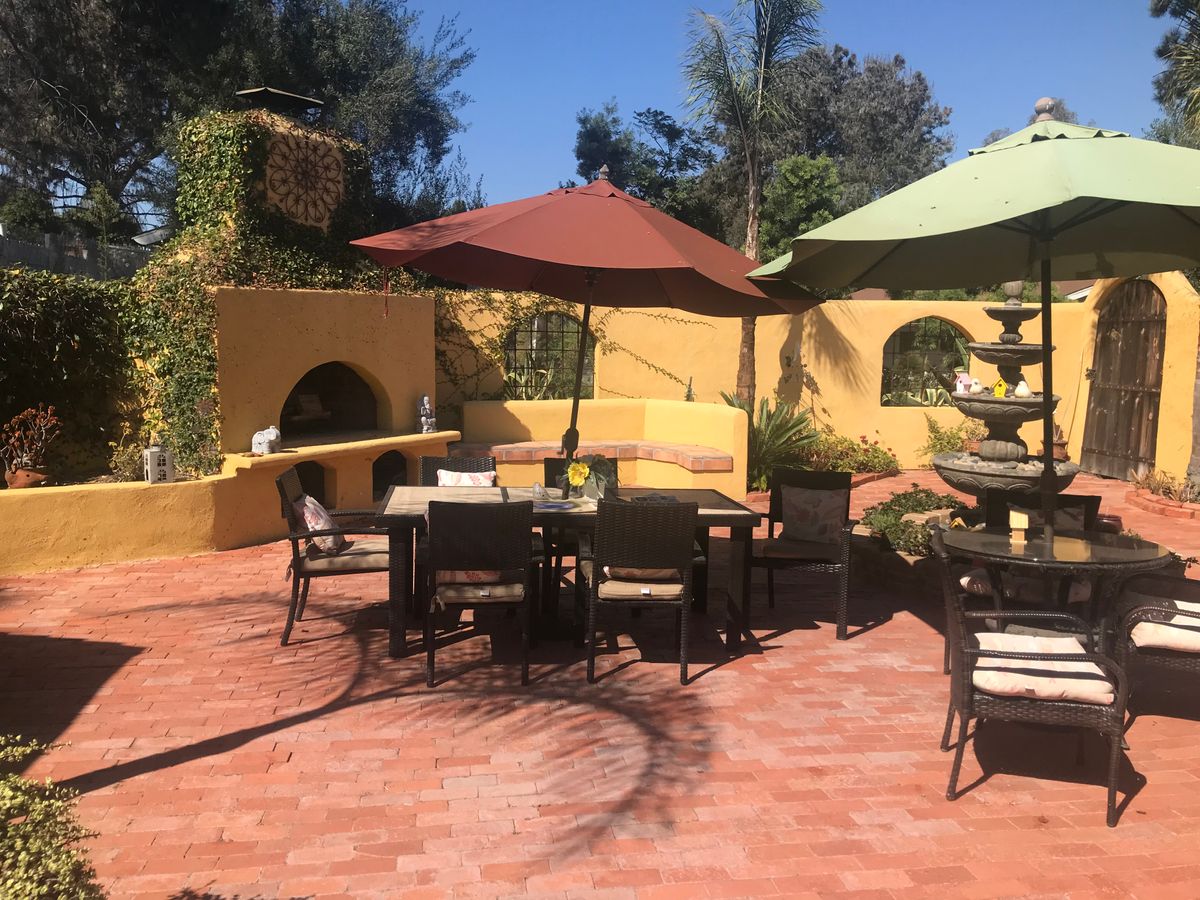 A cozy patio with seating and umbrellas under a sunny sky.