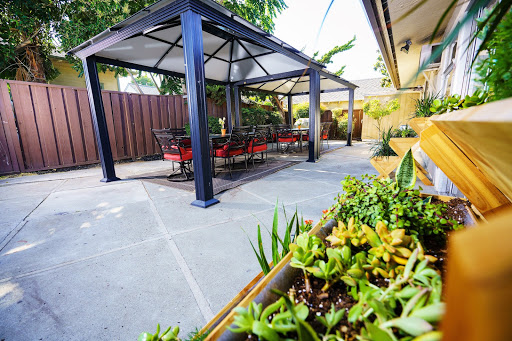A cozy outdoor space featuring a gazebo with seating, surrounded by lush greenery.