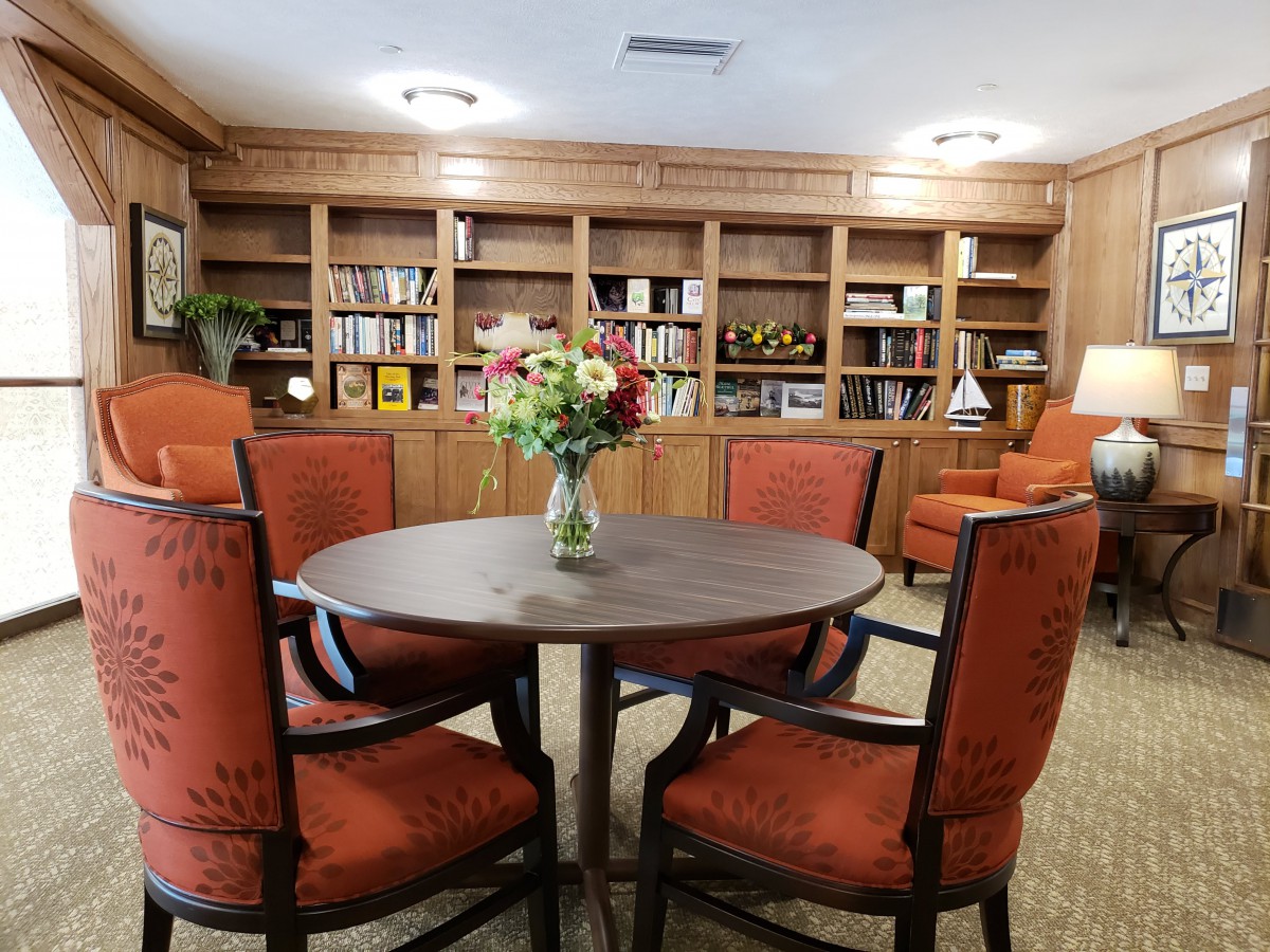 A cozy library space with a round table and chairs surrounded by bookshelves.