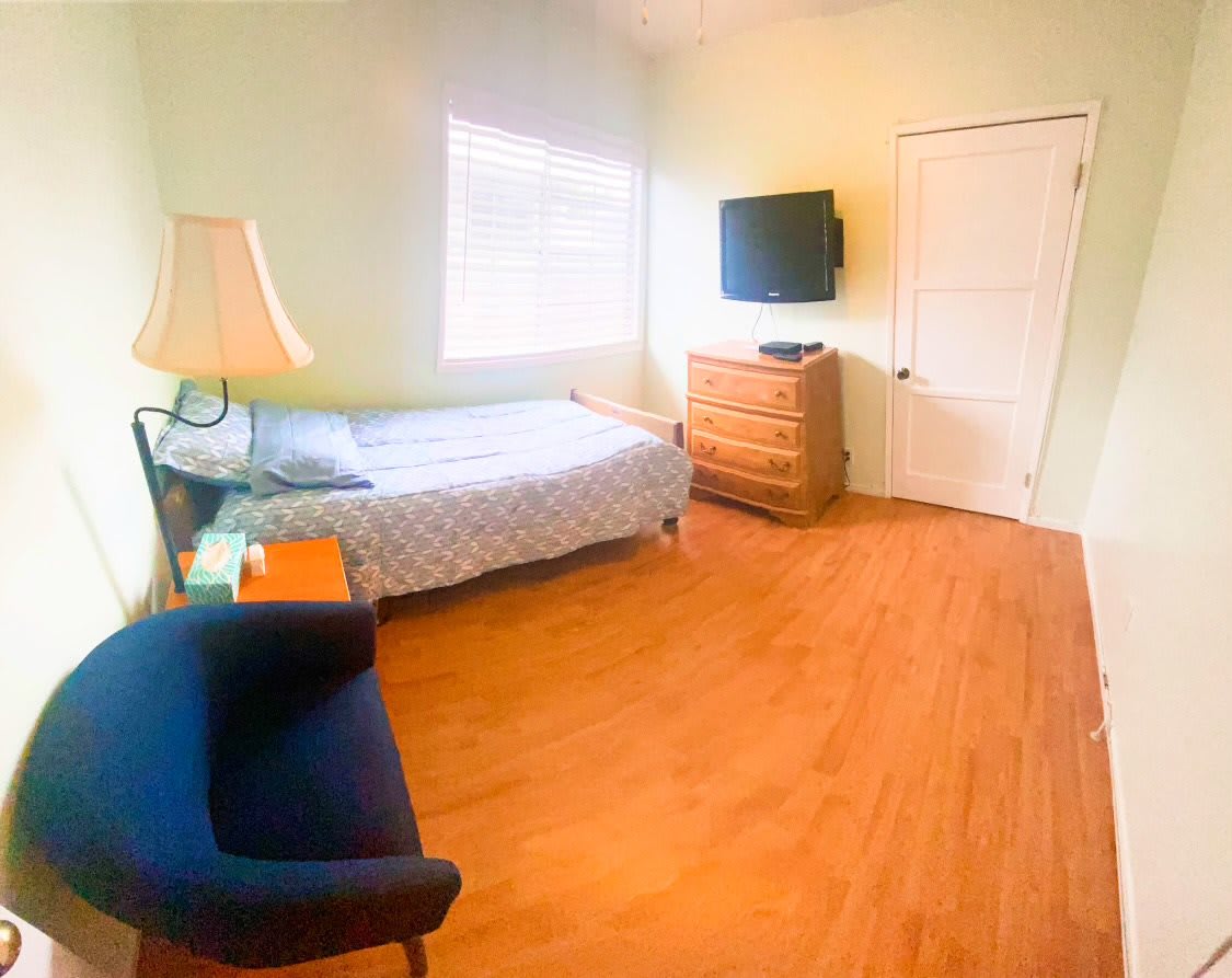 A cozy bedroom with a single bed, dresser, and flat-screen TV.