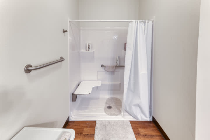 An ADA-compliant shower with a foldable seat and safety grab bars.