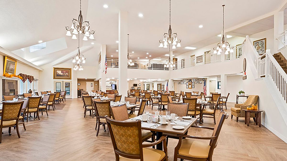 A spacious dining area with elegant chandeliers and neatly arranged tables and chairs.