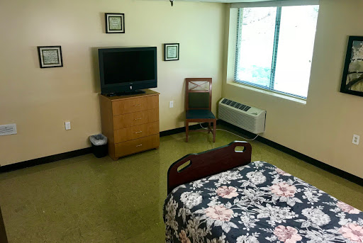 A hospital room featuring a bed, television, and a window.