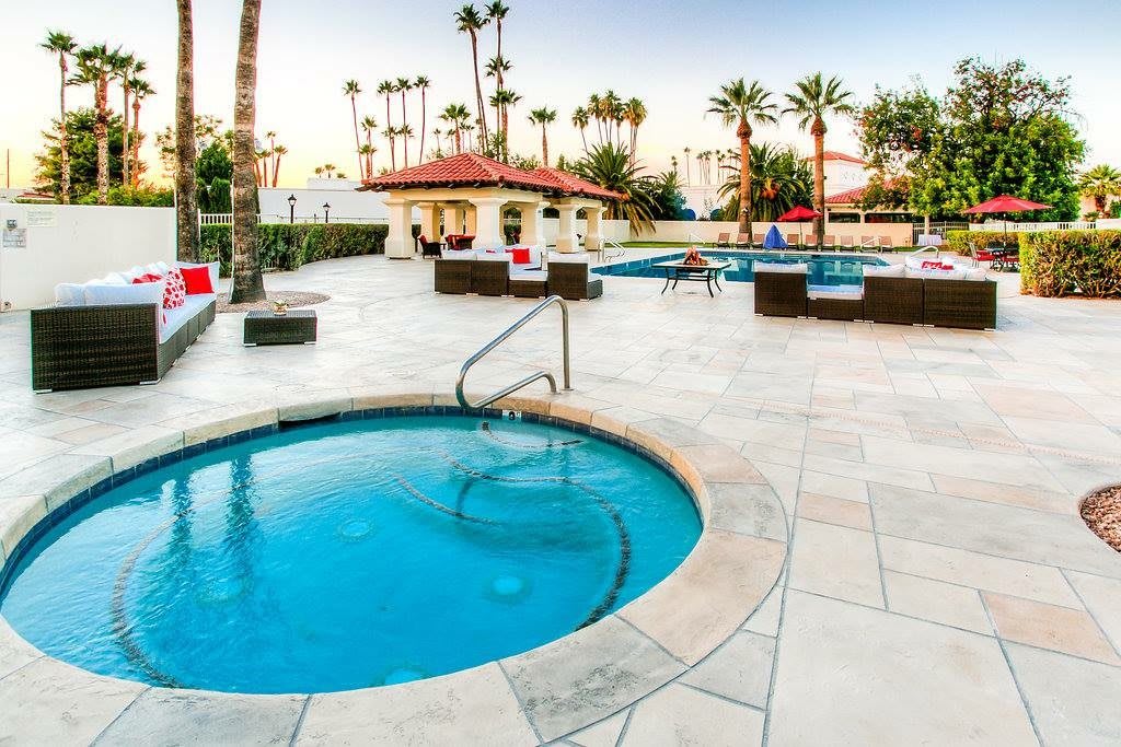 An inviting outdoor pool area surrounded by palm trees and comfortable lounging spaces.