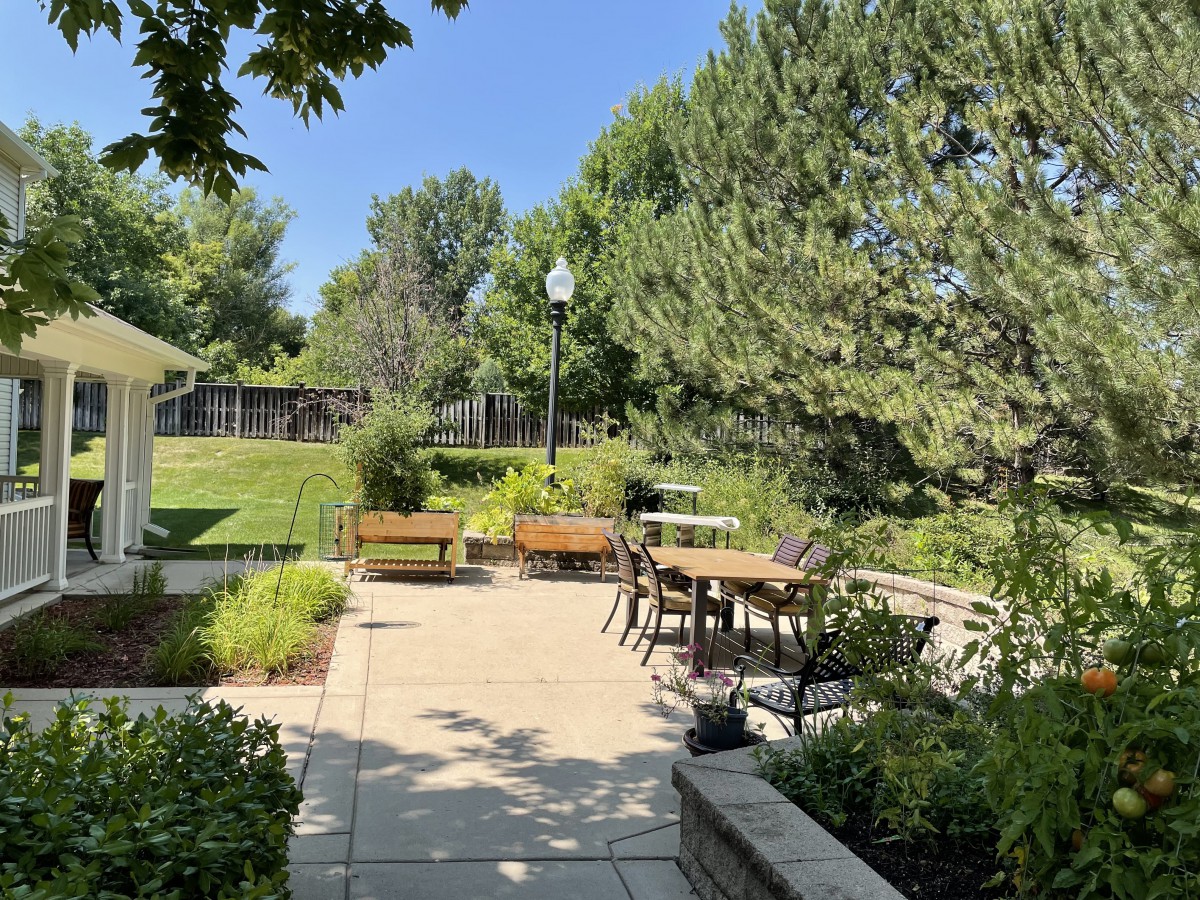 A serene outdoor patio area with tables and chairs surrounded by lush greenery.
