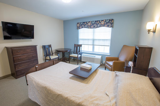 A cozy and well-furnished room featuring a bed, table, chairs, and a television.