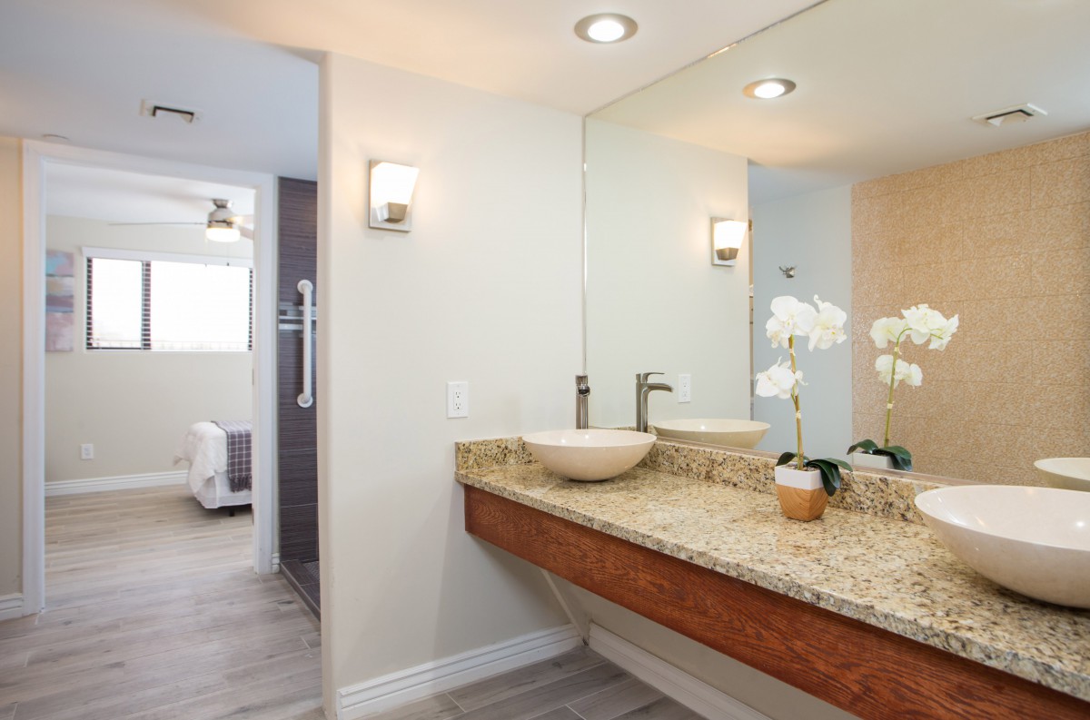 A modern bathroom interior featuring a sleek sink, large mirror, and contemporary lighting.