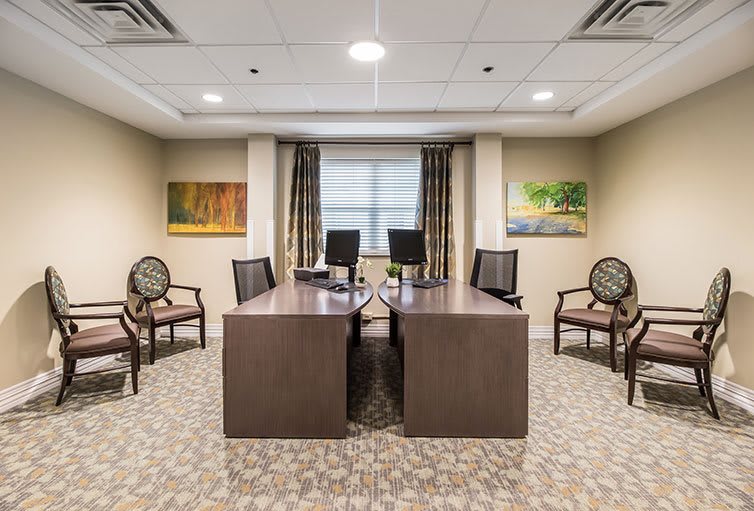 A well-furnished office conference room with desks and chairs around a meeting area.