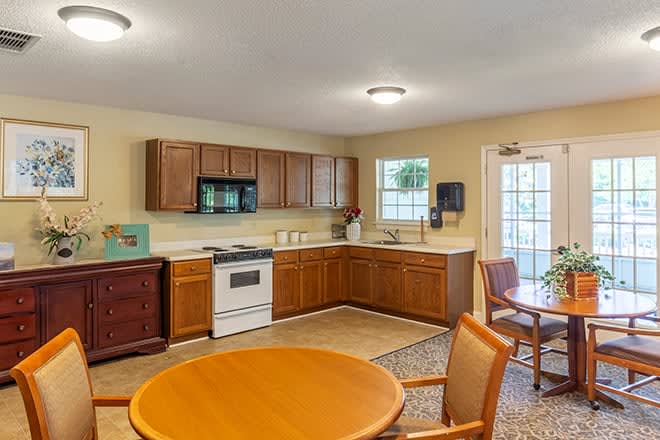A cozy kitchen and dining area with wooden cabinets, a round table with chairs, and standard kitchen appliances.