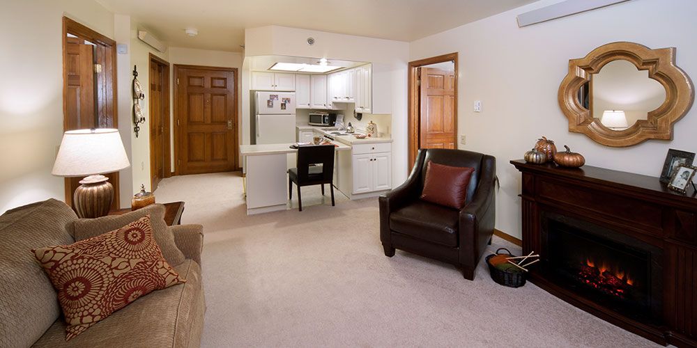 A cozy living room with an open kitchen layout, featuring comfortable furniture and a warm atmosphere.