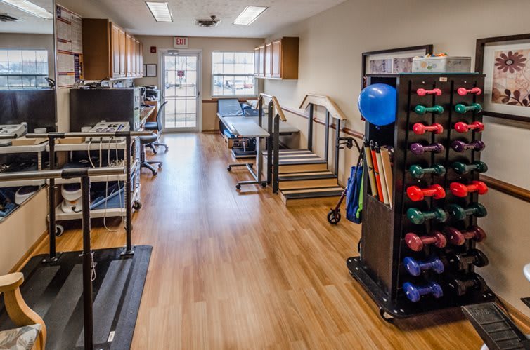 A well-equipped physical therapy and rehabilitation room with various exercise equipment and weights.
