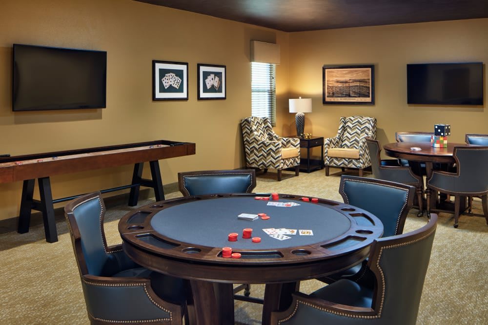 A cozy poker room featuring a gaming table with cards and chips, surrounded by comfortable chairs and warm lighting.