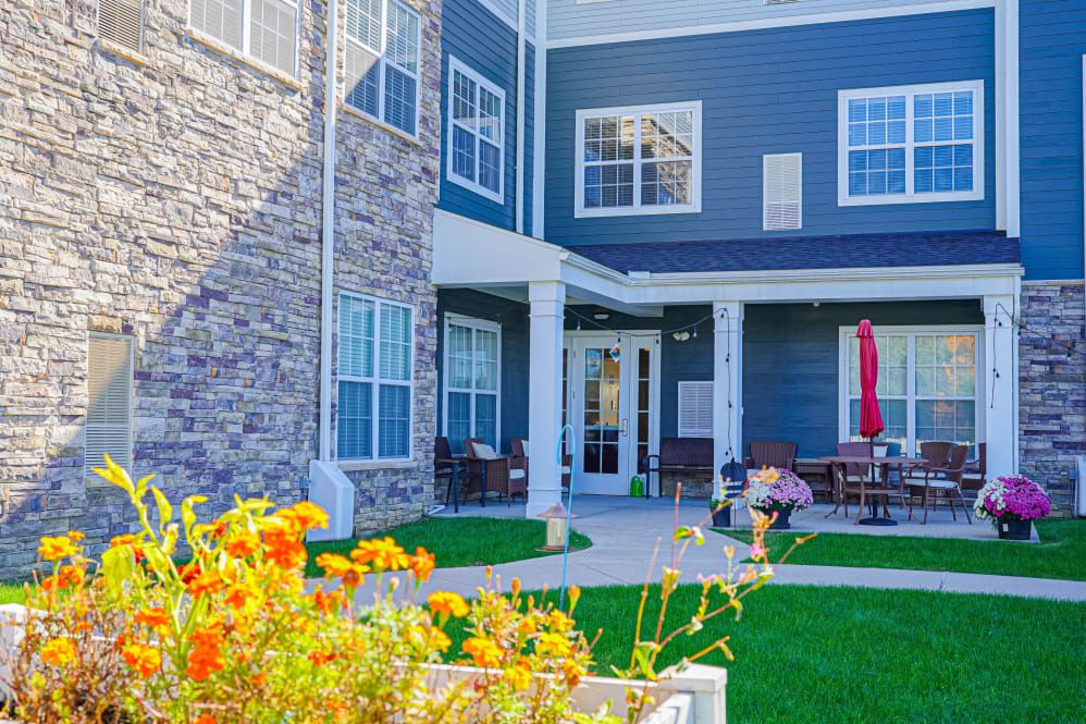 A residential building with a courtyard featuring flowers and a patio area.