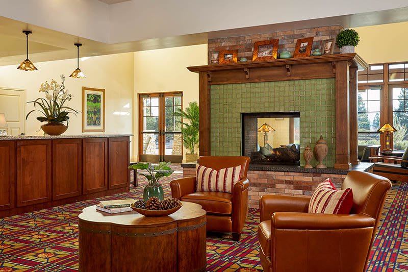 A cozy living room featuring a fireplace with green tiles and comfortable leather chairs.