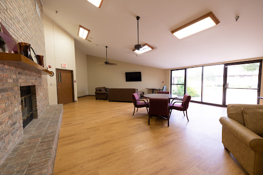 A spacious lounge with wooden flooring and ample natural light, featuring comfortable seating.