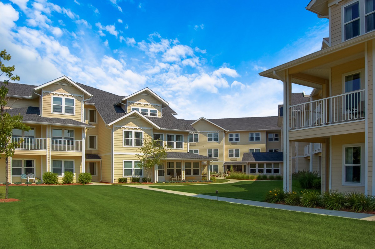 A residential apartment building with a well-maintained green lawn and a clear blue sky.