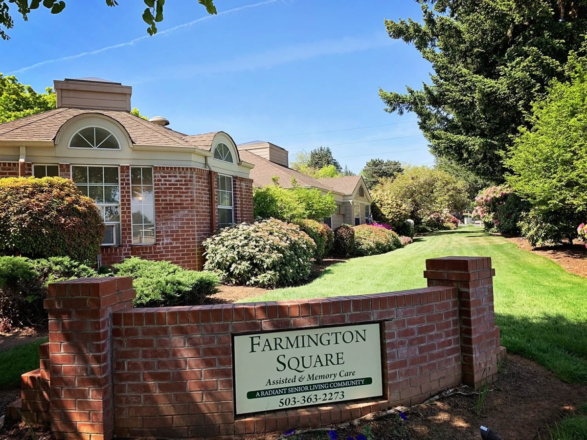 A well-maintained building surrounded by lush landscaping with a sign reading 'Farmington Square' in the foreground.