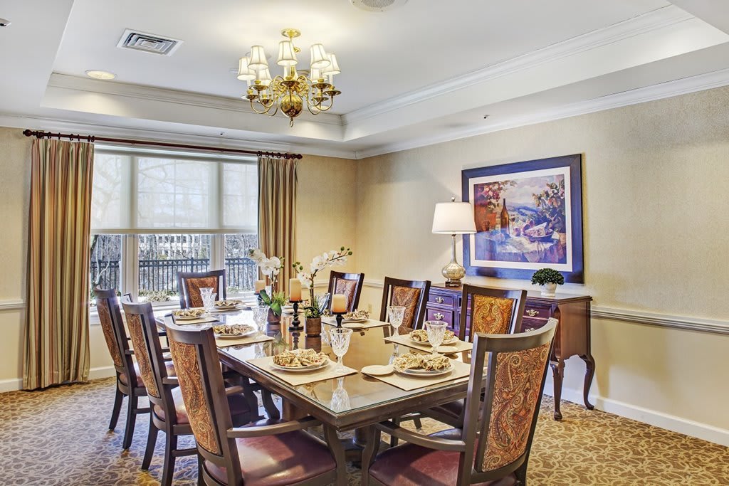 A traditional dining room with an elegantly set table and chandelier.