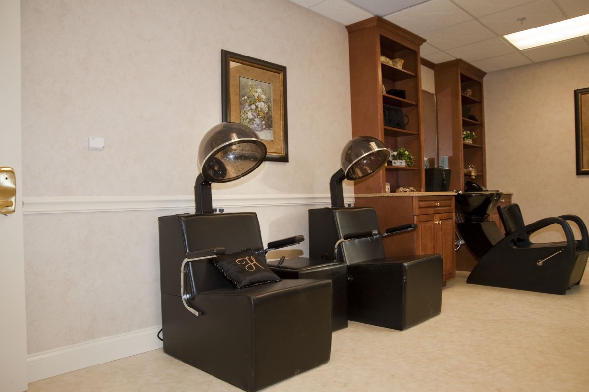 A hair salon interior featuring hairdryer chairs and elegant wooden shelves.