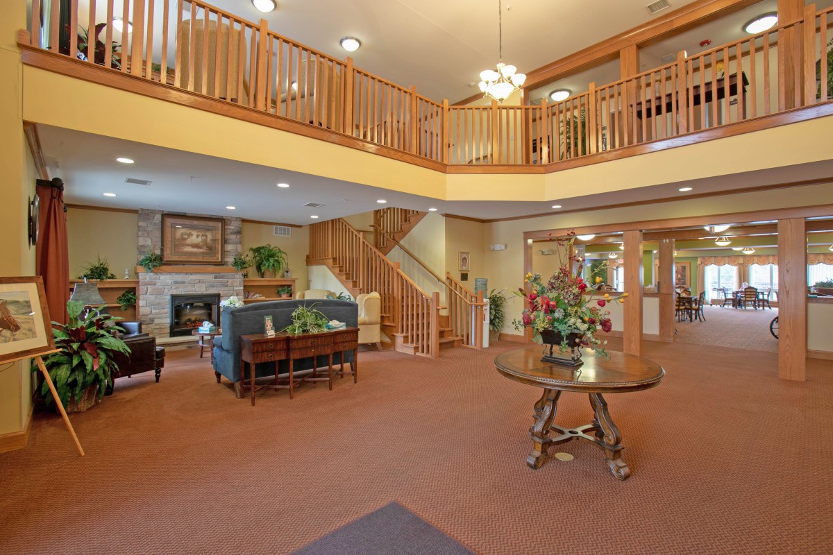 A spacious two-story lobby with comfortable seating, wooden railings, and a decorative chandelier.