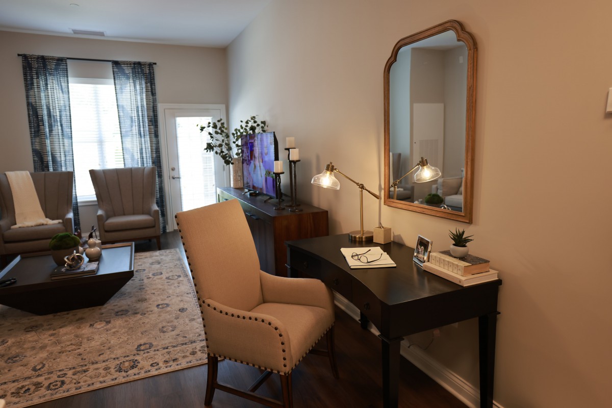 A cozy living space featuring a desk with a chair, mirror, and decorative items.