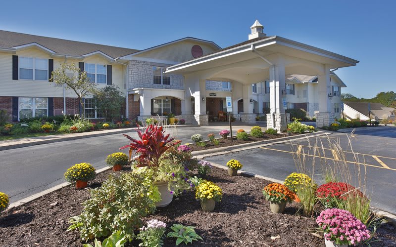 A well-landscaped entrance of a modern building with vibrant flowers and greenery.