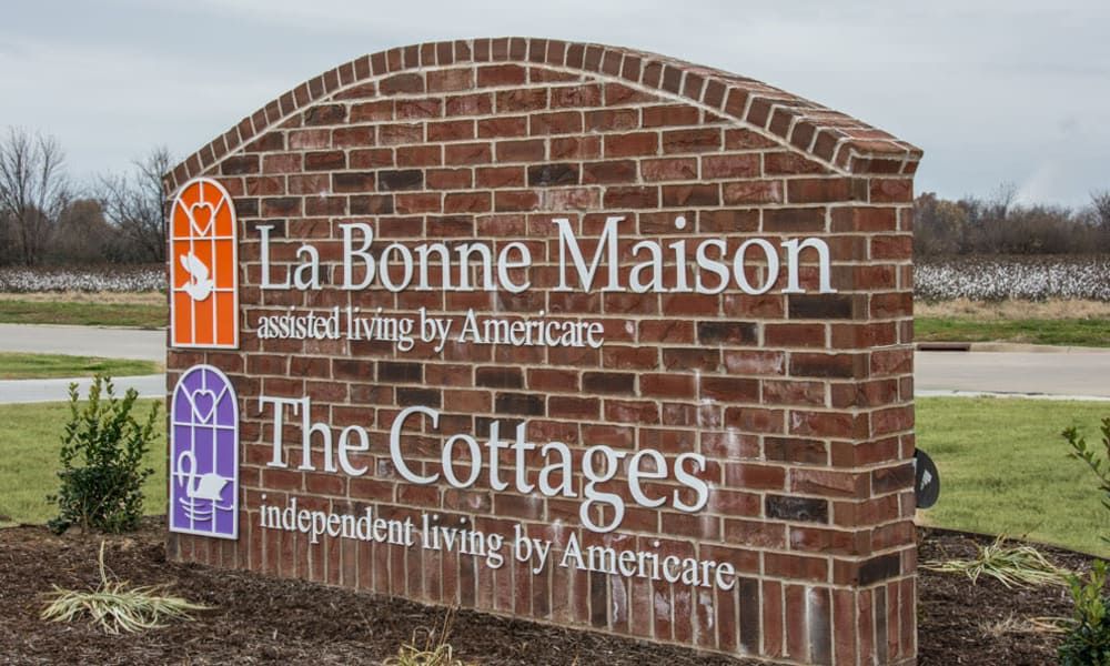 A brick sign for La Bonne Maison Assisted Living and The Cottages Independent Living by Americare.