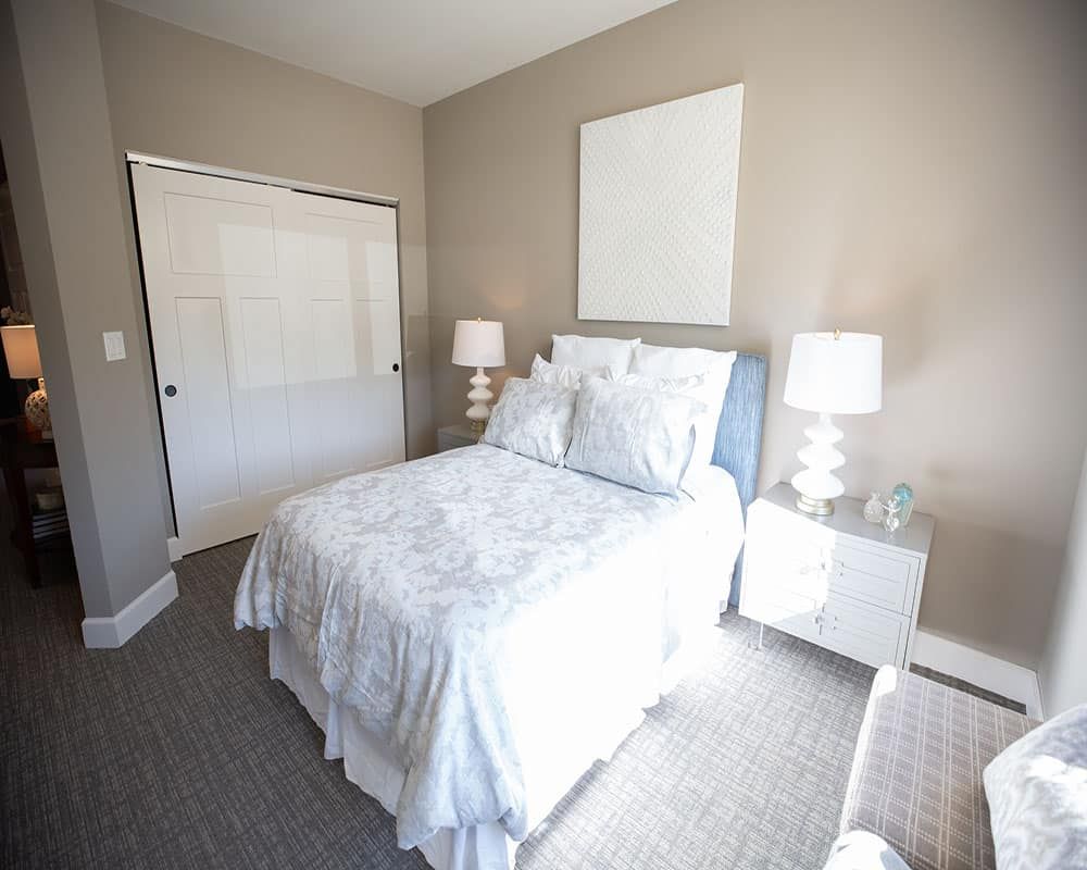 A modern bedroom with a neatly made bed, two lamps, and matching nightstands.