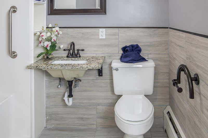 A modern bathroom with a toilet, sink, and orchid decoration.