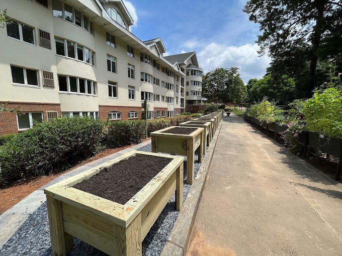 Raised planter boxes lined up along a pathway next to a building.