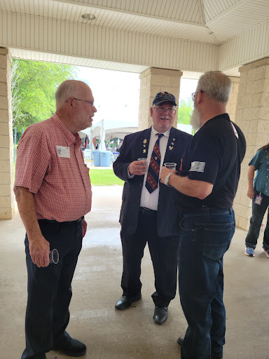 A group of men engaged in conversation at an outdoor event.