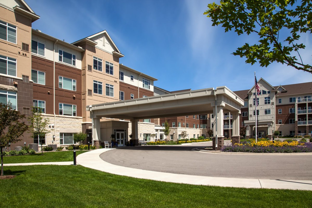 A modern residential building with a covered entrance and landscaped surroundings.