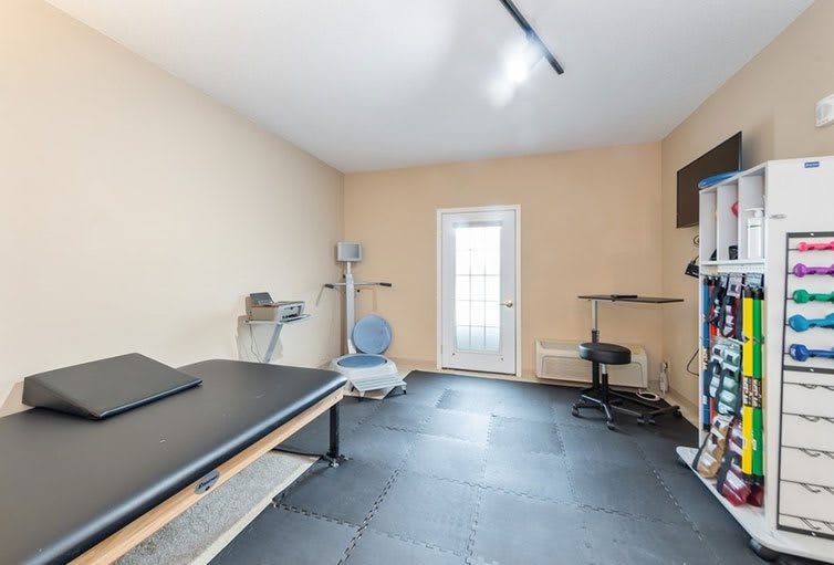 A tidy home gym equipped with various exercise equipment and a rubber flooring.