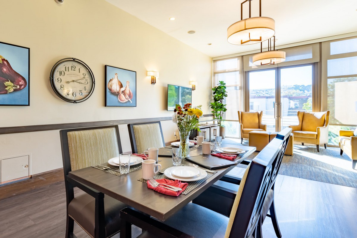 A well-lit dining room with a set table, featuring sunflowers and modern decor.