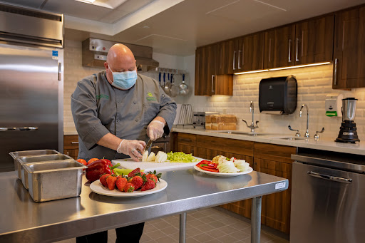 A chef in a professional kitchen prepares fresh ingredients while following safety protocols.