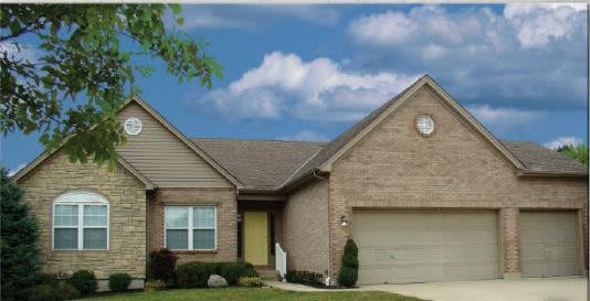 A suburban house with a brick exterior and attached garage under a cloudy sky.