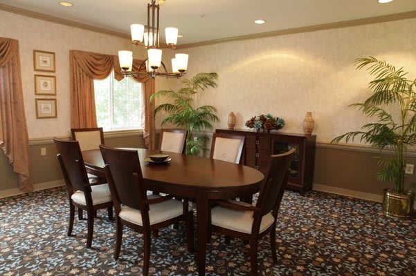 A cozy dining room with a wooden table and chairs, illuminated by a chandelier.