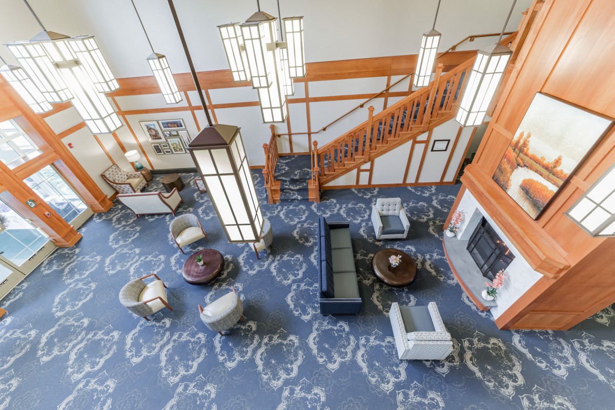 A spacious lobby area with modern furniture, decorative lighting, and an elegant staircase.