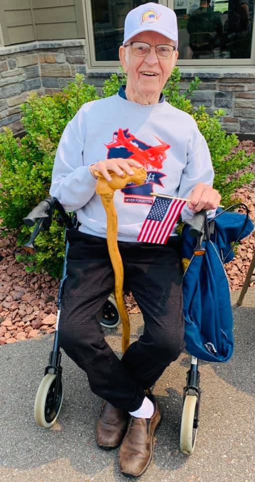 A person sitting outdoors is holding a snake and an American flag.
